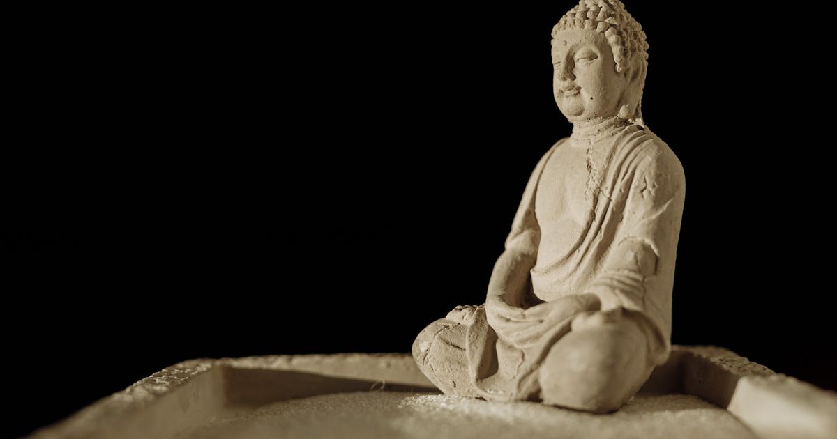 Mjedeni kip Bude koji sjedi u meditativnom položaju kao smiren dekorativni element kućnog interijera
