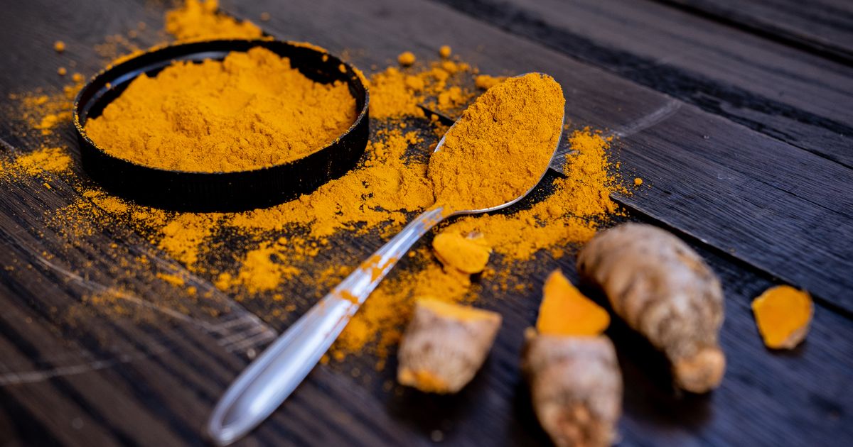 Kurkuma — mljeveni prah kurkume i korijen Curcuma longa na drvenoj dasci