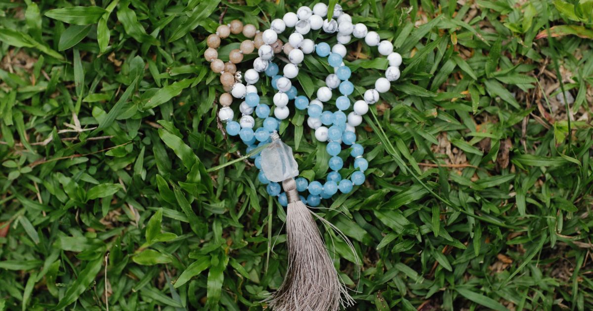 Mala – meditativne molitvene perle sa 108 perli i guru perlom položene na drvenoj podlozi